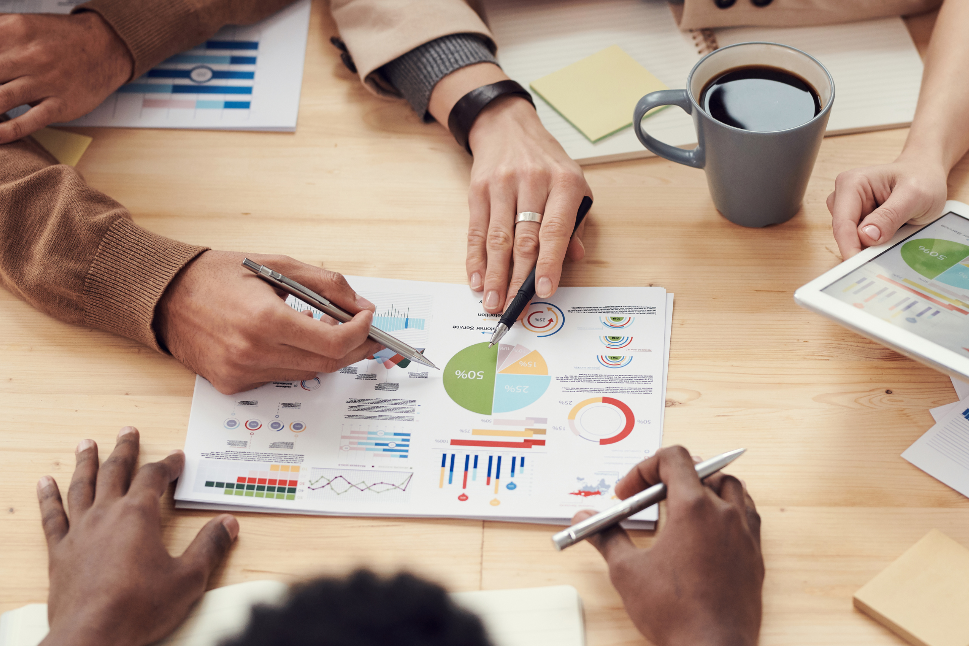 A group of people are sitting at a table looking at a pie chart.