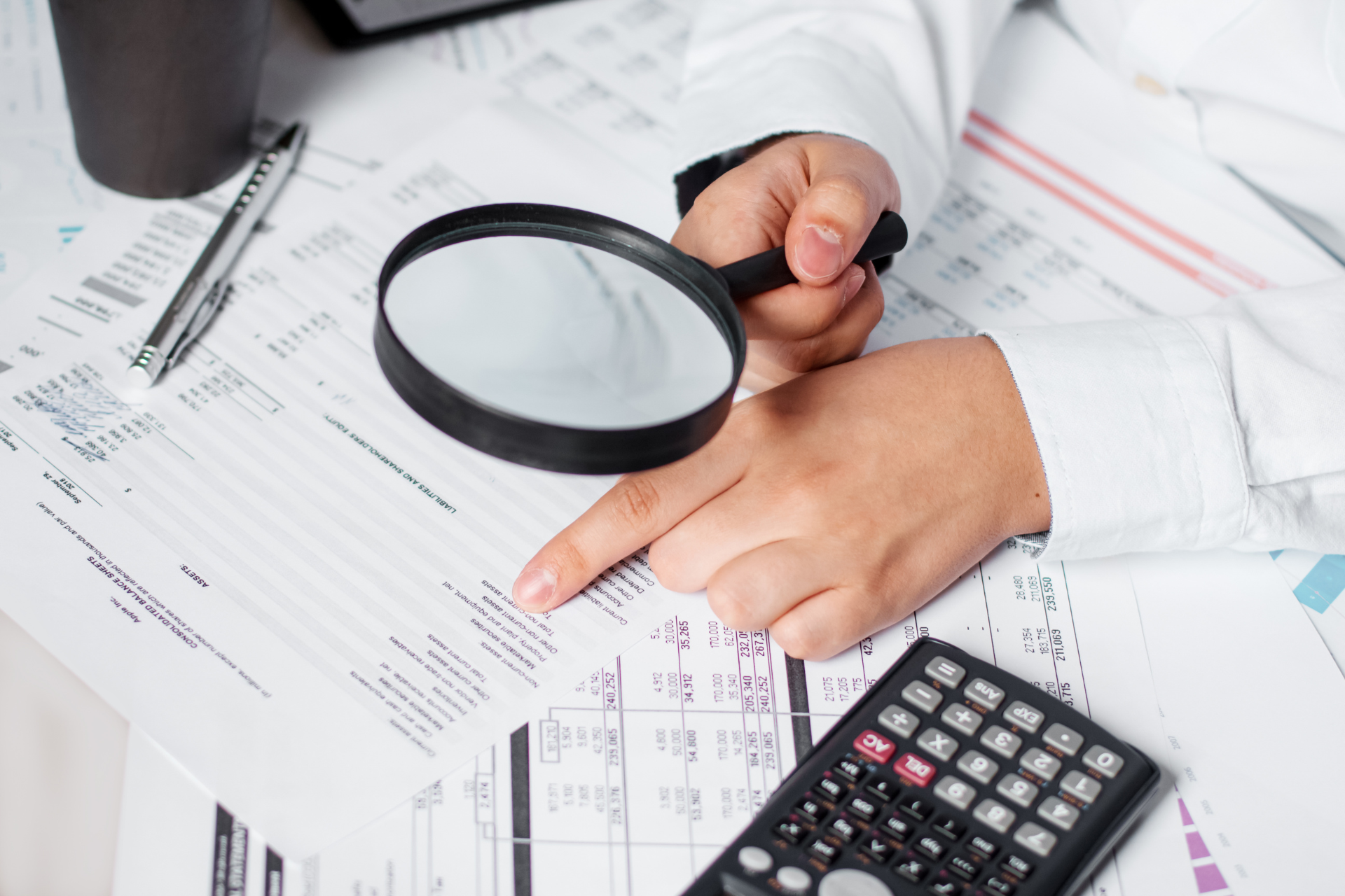 A person is using a magnifying glass to look at a piece of paper.