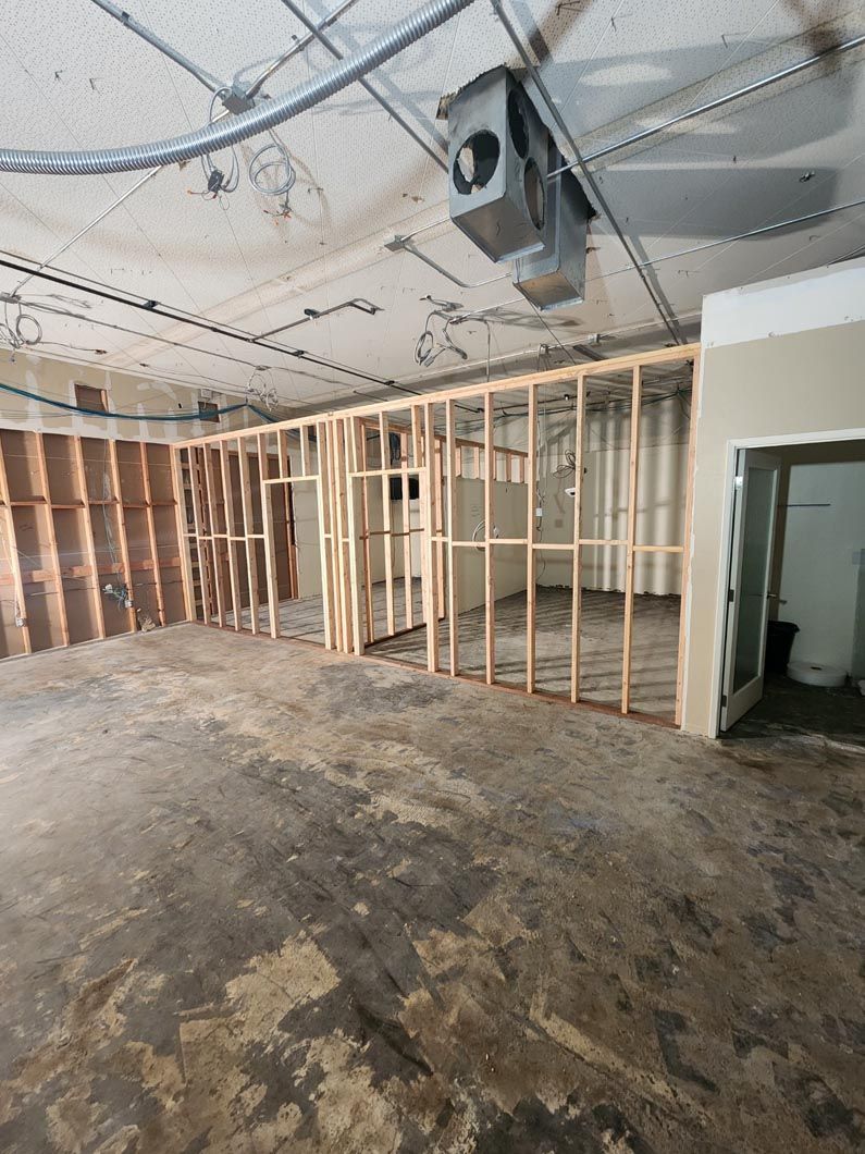 A large empty room with wooden walls and a ceiling fan.