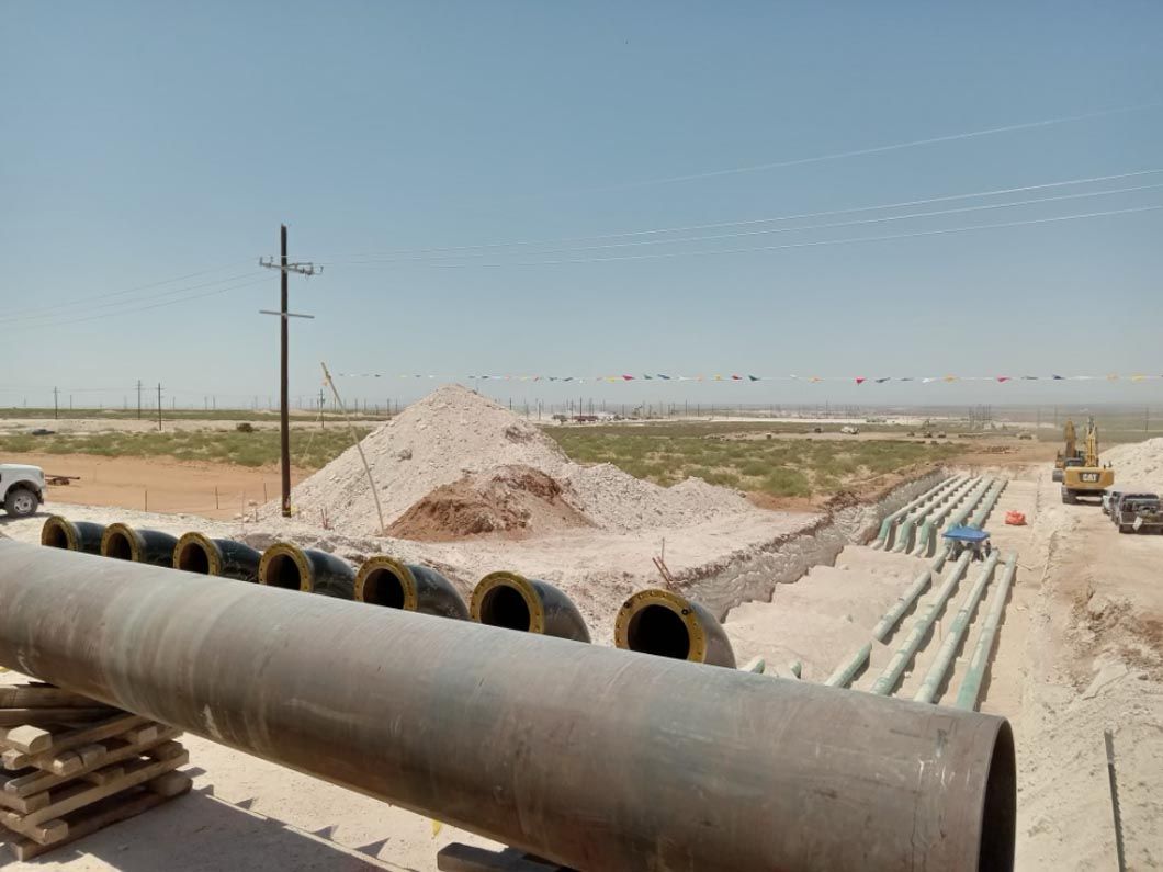 A large pipe is sitting in the middle of a dirt field.