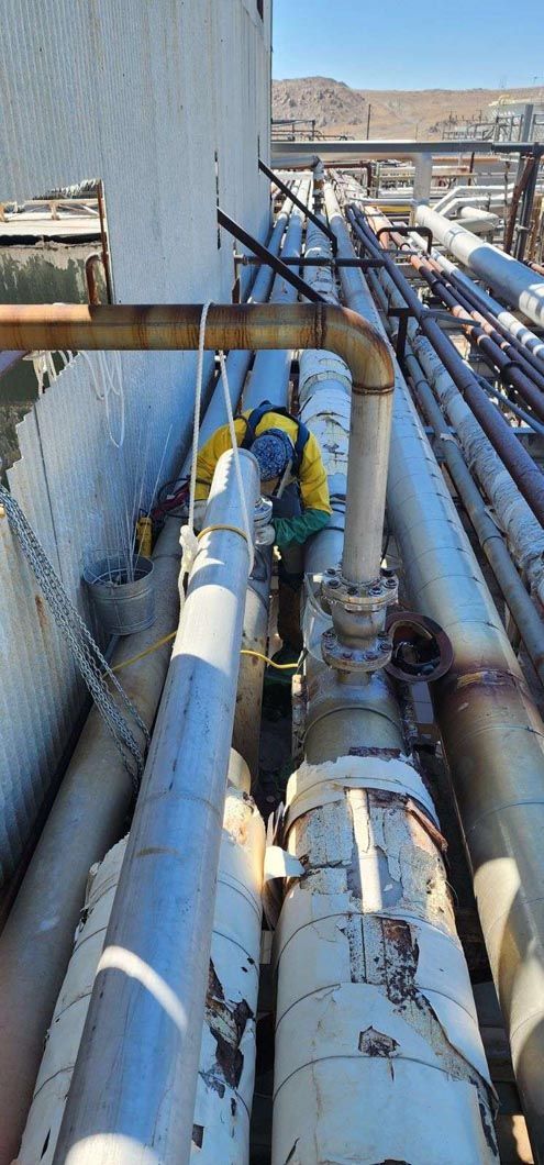 A man is working on a bunch of pipes in a factory.