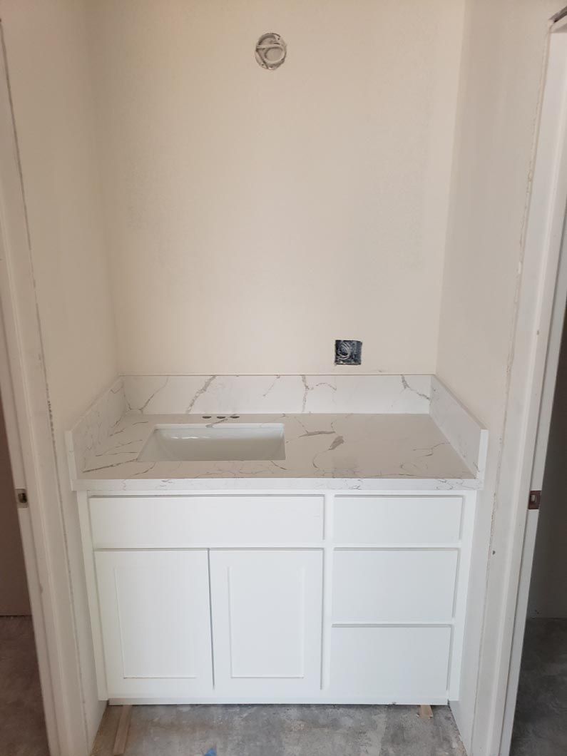A bathroom vanity with a sink and a marble counter top.