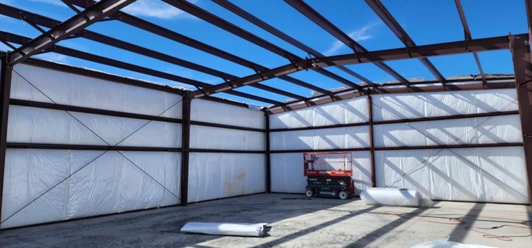A large metal building under construction with a blue sky in the background.