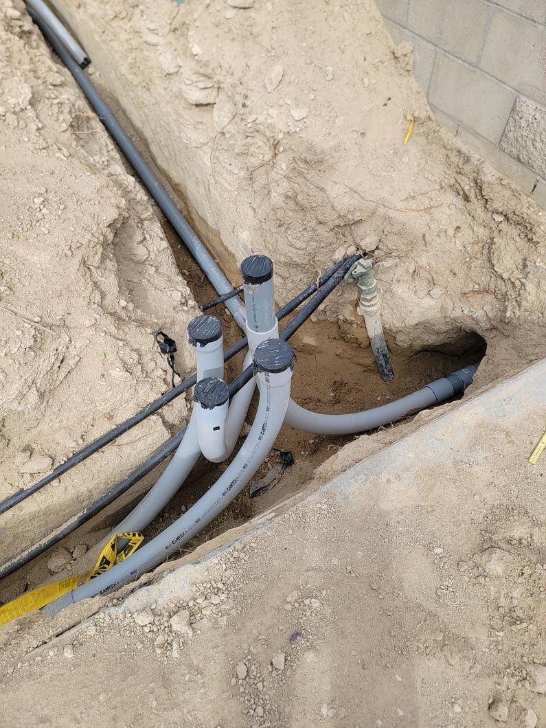 A bunch of pipes are laying in the dirt.