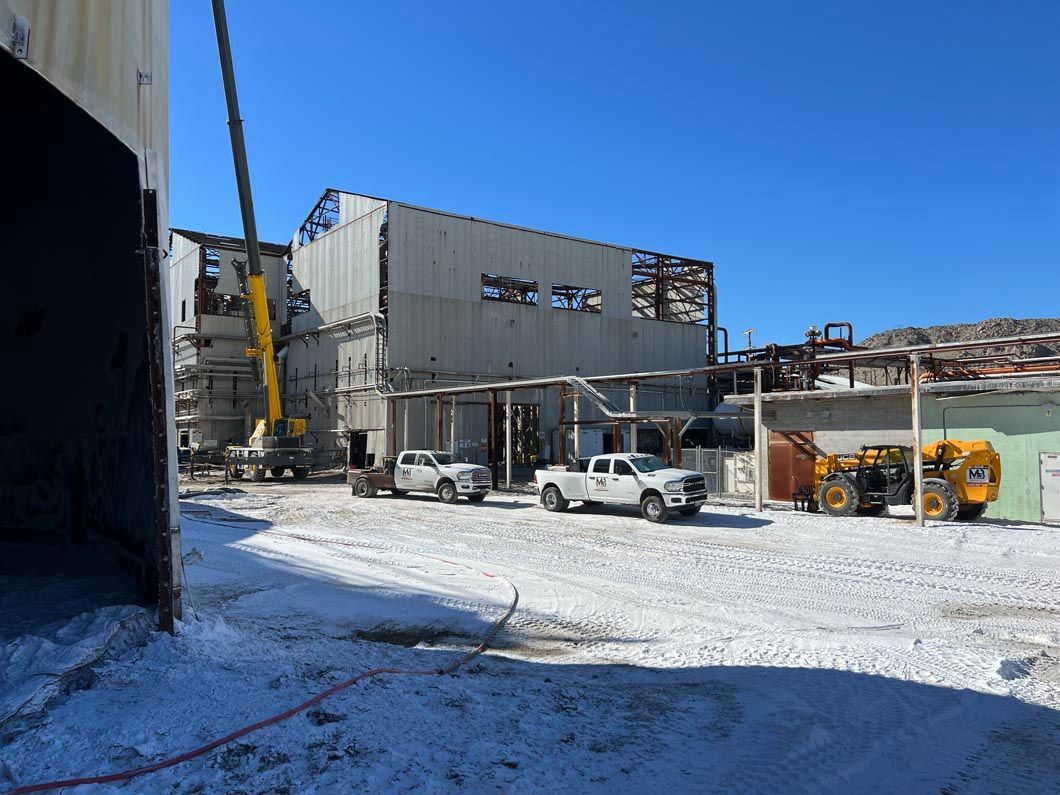 A large building is being demolished and trucks are parked in front of it.