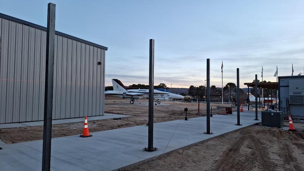 A fence is being built in front of a building with a plane in the background.
