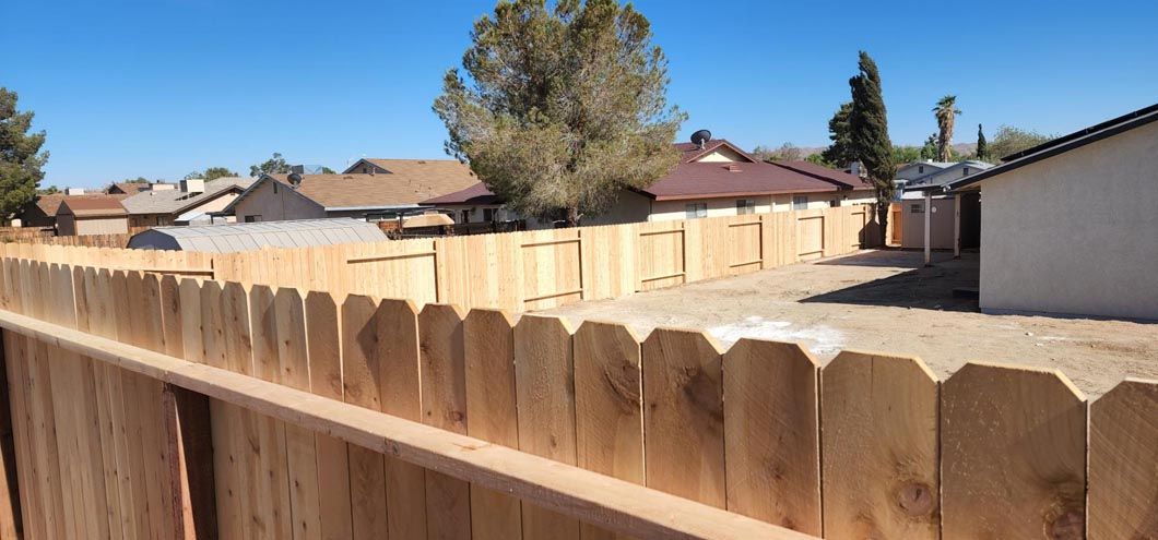 A wooden fence is sitting in front of a house in a residential area.
