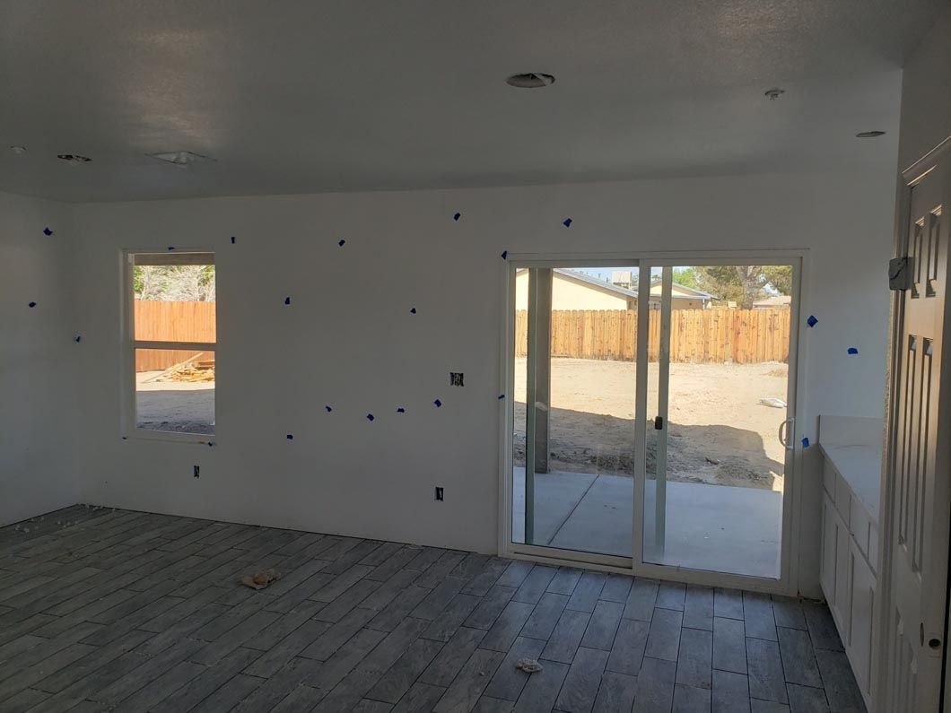 An empty room with a sliding glass door and two windows.