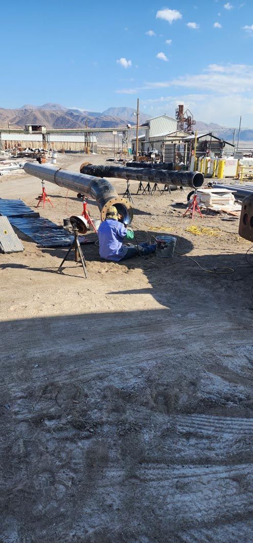 A man is sitting on the ground next to a plane in a field.