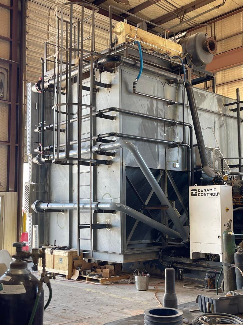A large transformer is sitting inside of a building in a factory.