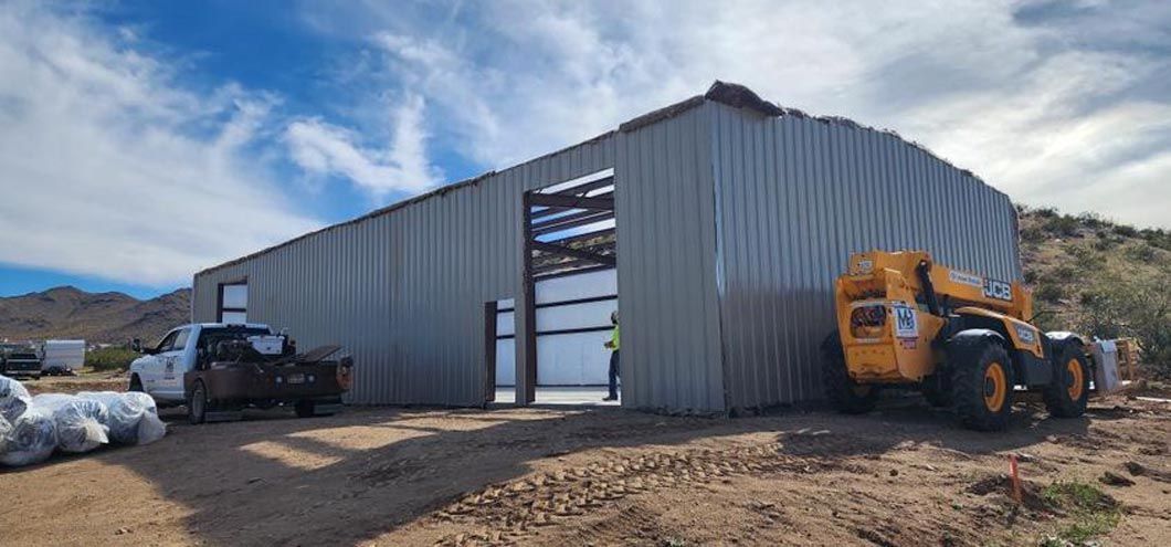 A tractor is parked in front of a large metal building.