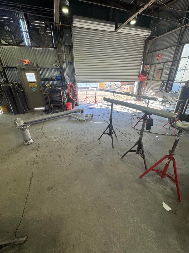 A garage with a garage door open and a lot of tools on the floor.