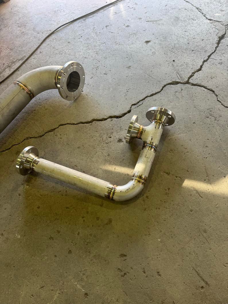 A pair of metal pipes are laying on a cracked concrete floor.