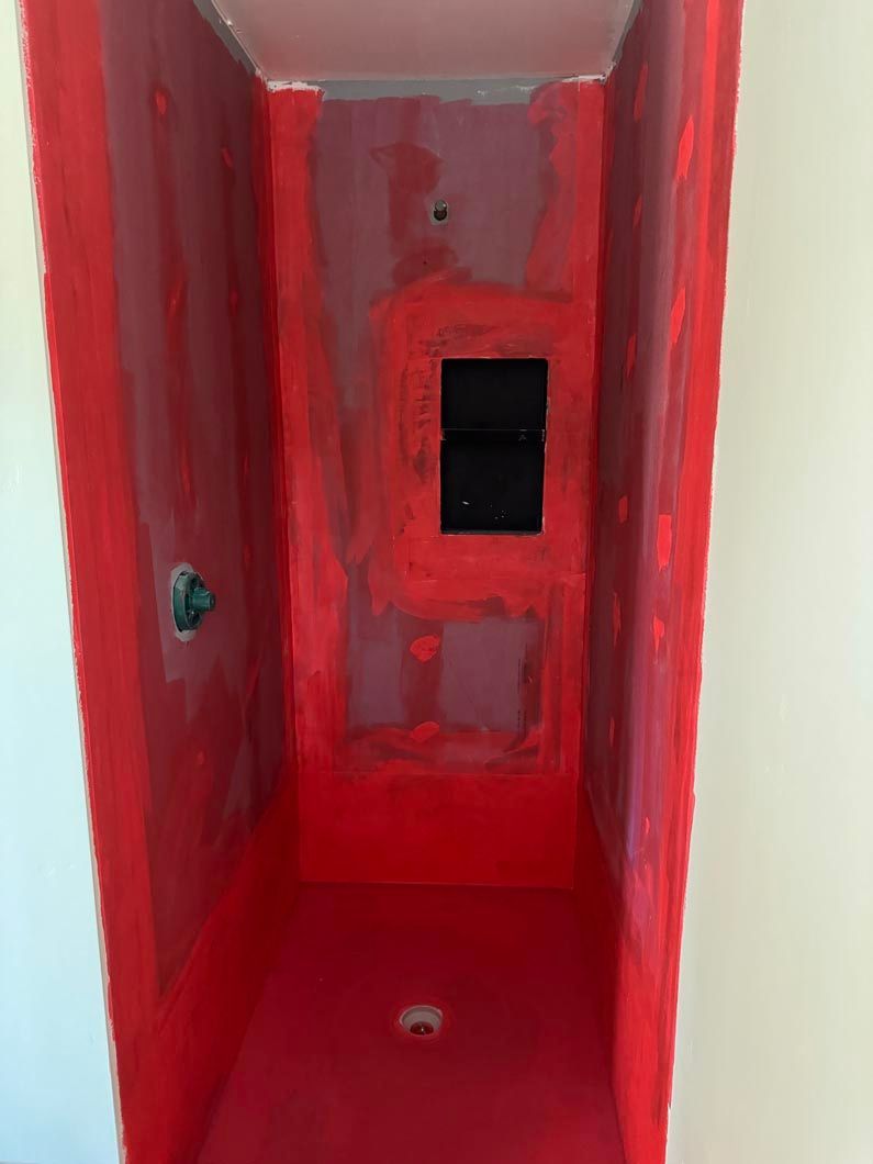 A shower stall with red paint on the walls and floor.