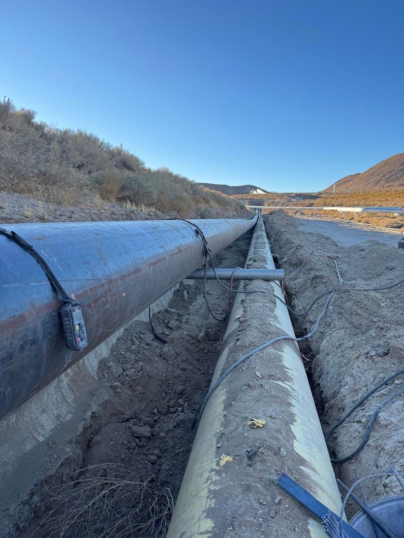 A row of pipes sitting in the dirt next to a road.