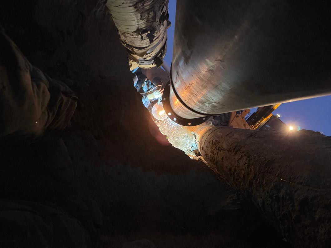 A person is welding a pipe in the dark.