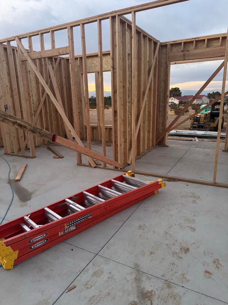 A red ladder is sitting in front of a building under construction.