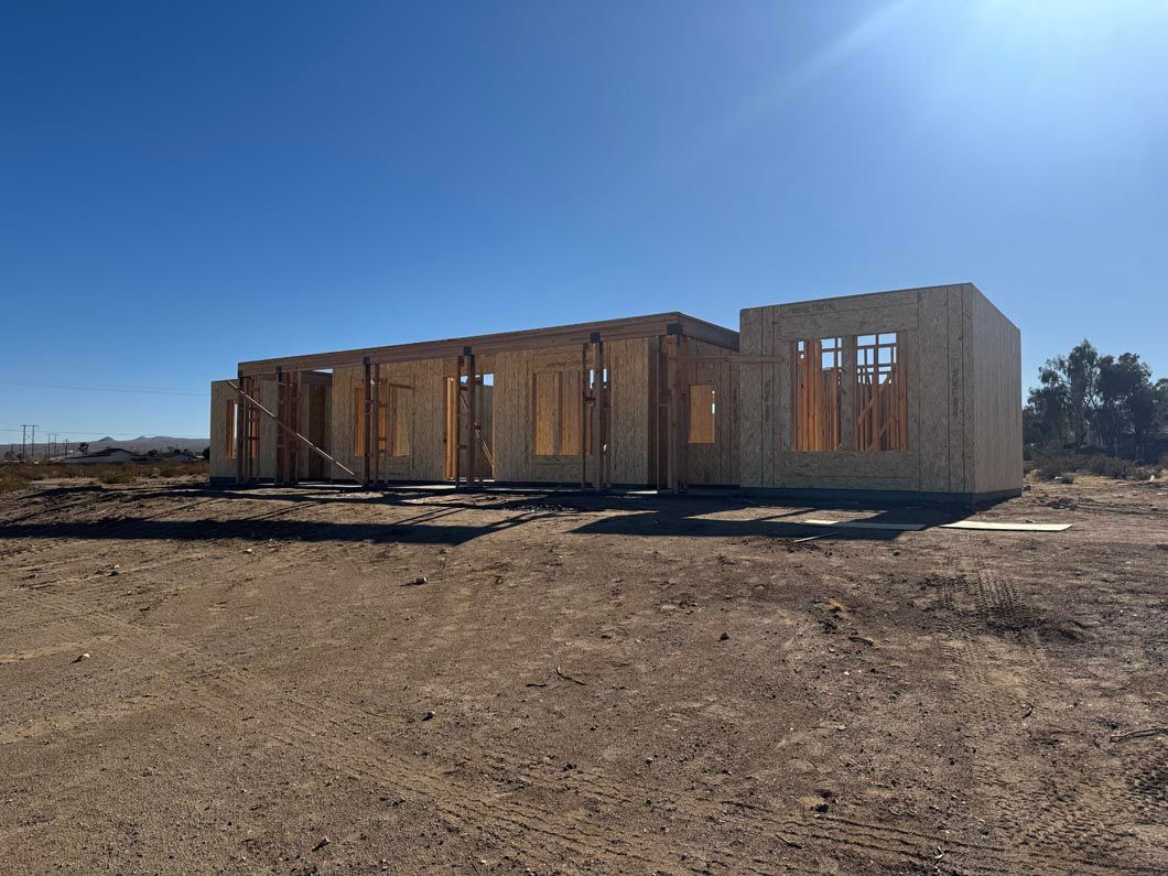 A house is being built in the middle of a dry grass field.