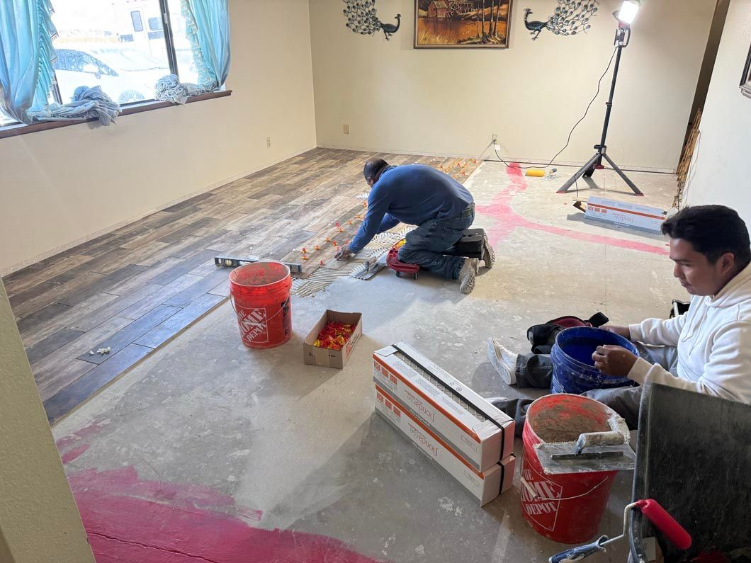 Two men are working on a wooden floor in a room.