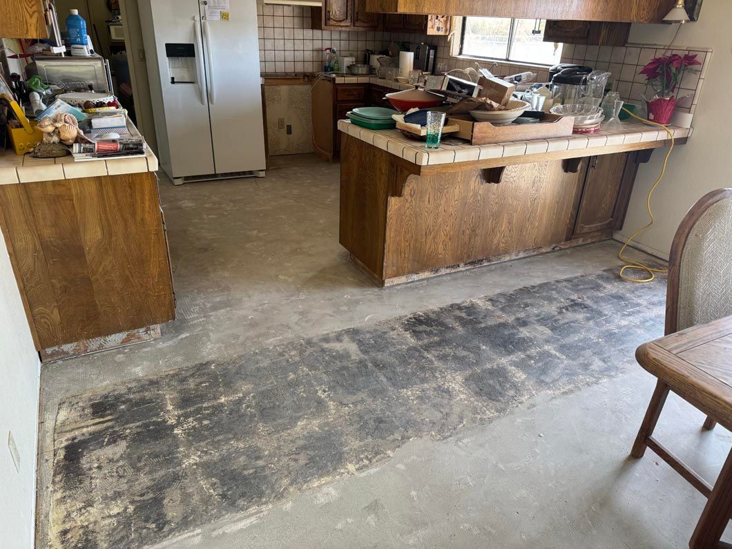 A kitchen with a dirty floor and a refrigerator.