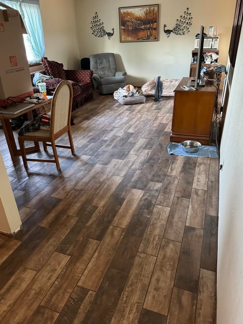 A living room with a wooden floor and a table and chairs.