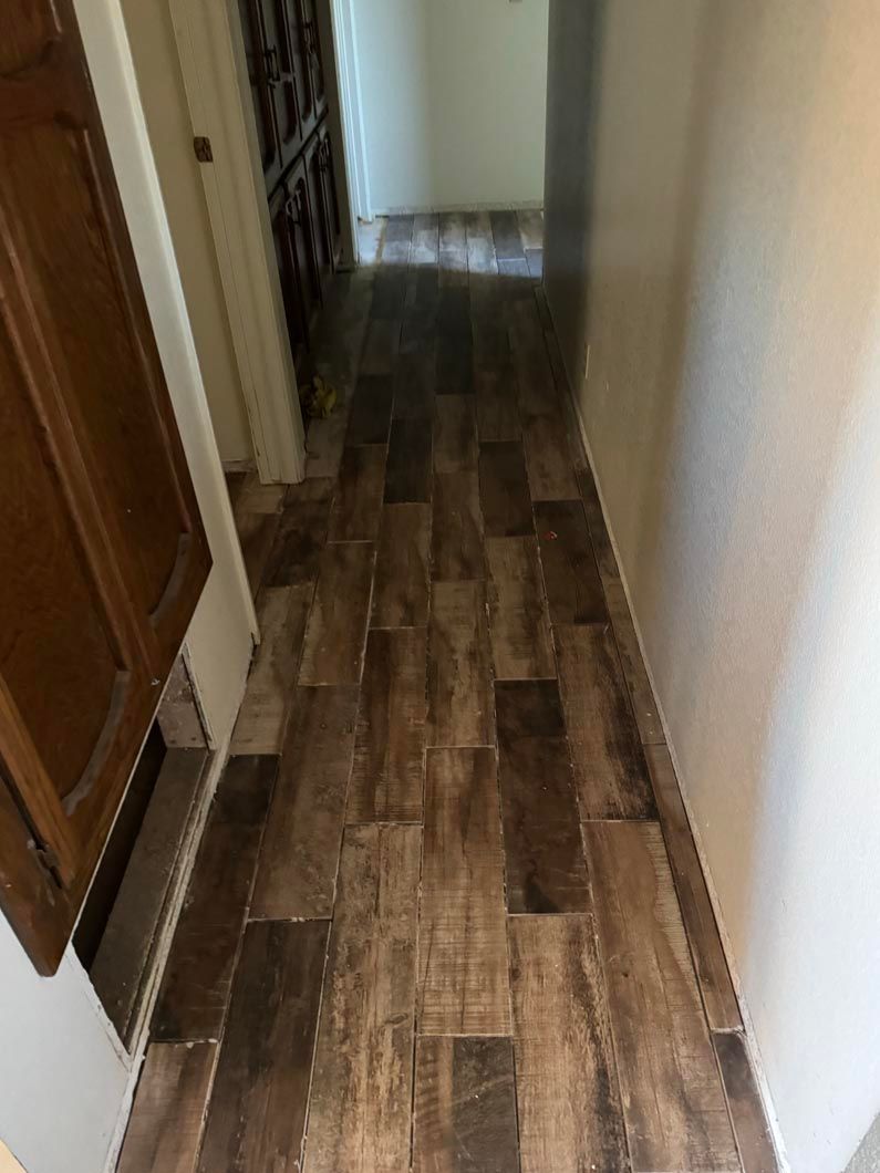A hallway with a wooden floor and a white wall.