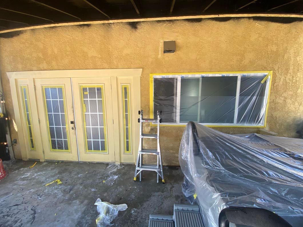 A ladder is sitting in front of a house that is being painted.