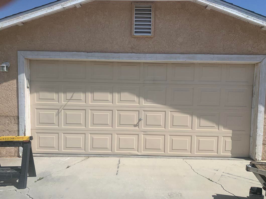 A beige garage door is sitting in front of a house.