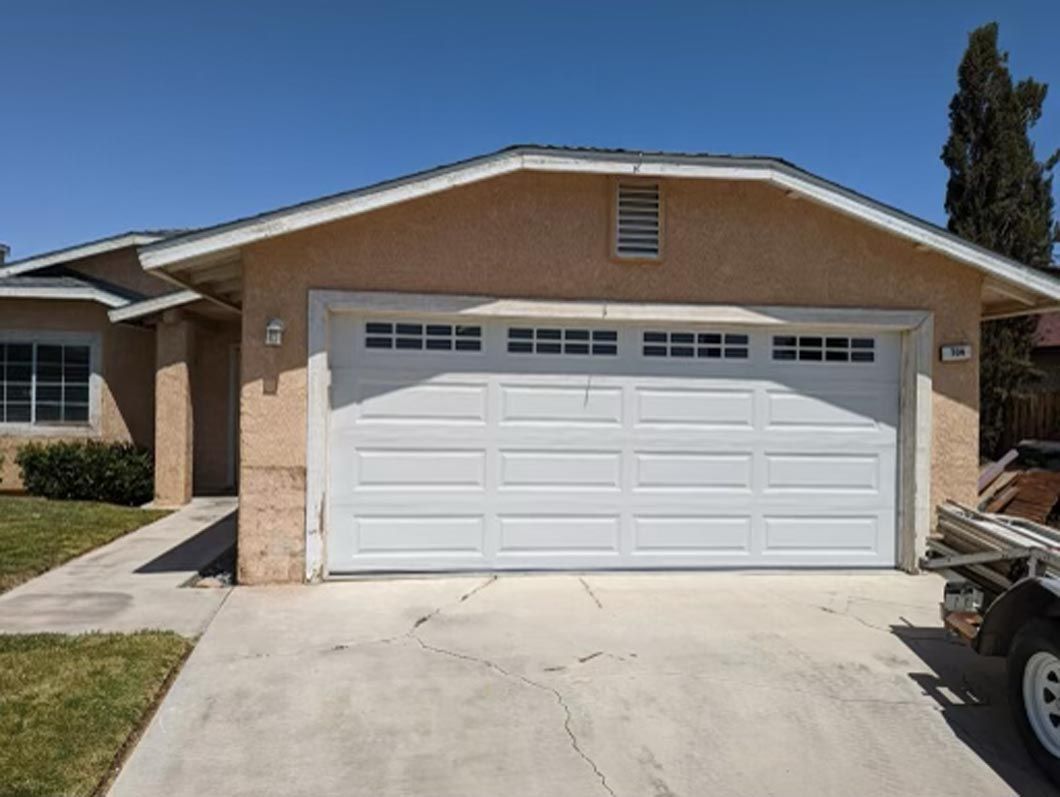 A car is parked in front of a house with a white garage door