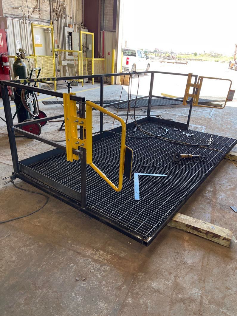 A metal platform with a yellow gate is being built in a factory.
