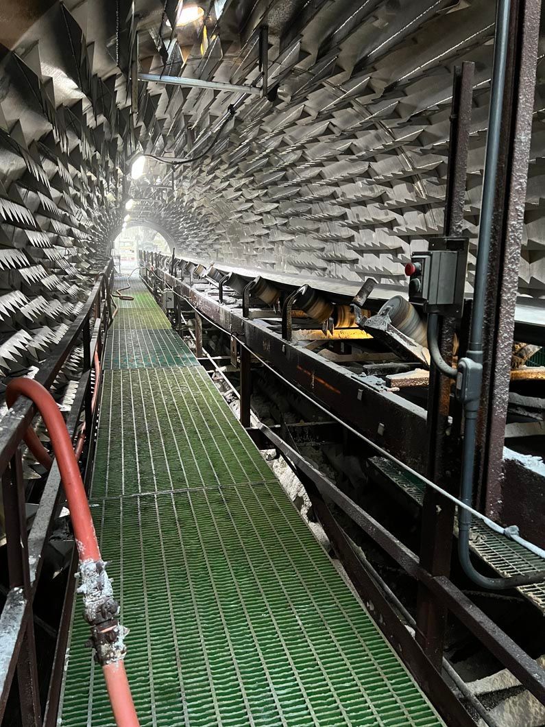 A hose is connected to a conveyor belt in a tunnel.