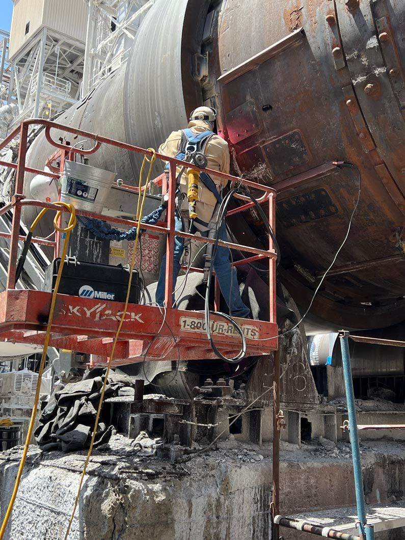 A man is standing on a platform next to a large pipe.