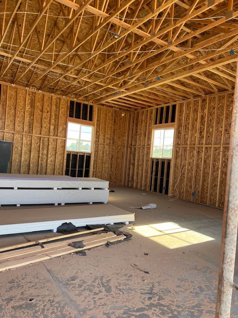 The inside of a building under construction with wooden beams and windows.