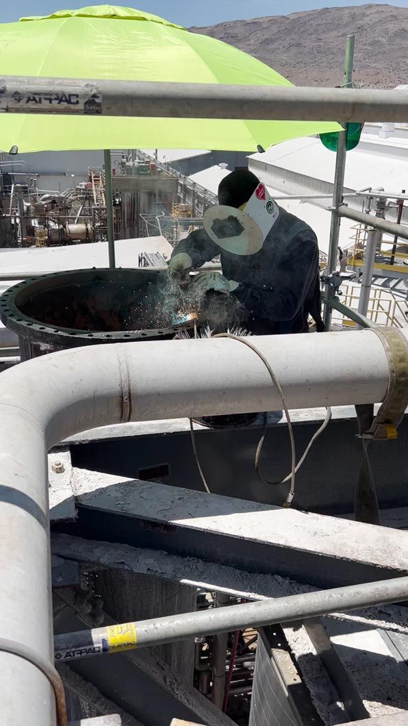 A man is welding a pipe in a factory.