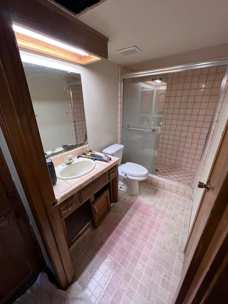 A bathroom with a sink , toilet , shower and mirror.