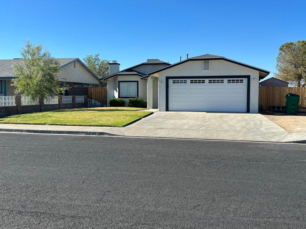 A house with a white garage door is sitting on the side of the road.