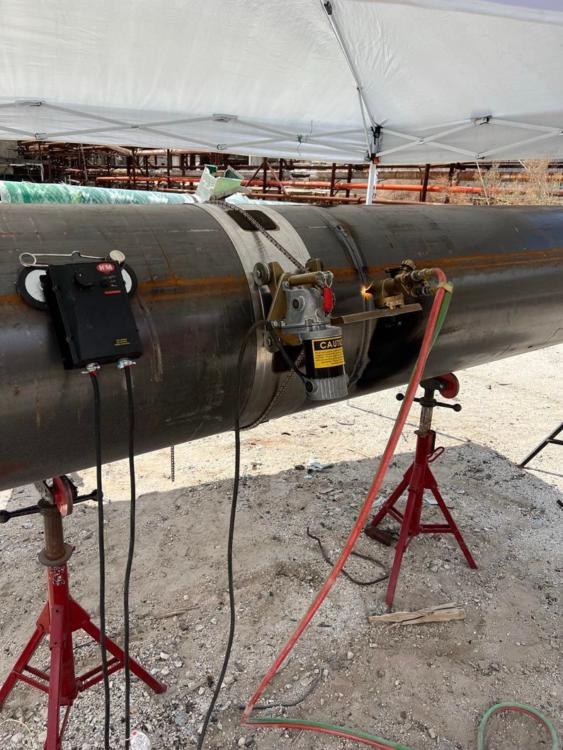 A pipe is being inspected by a machine under a tent.