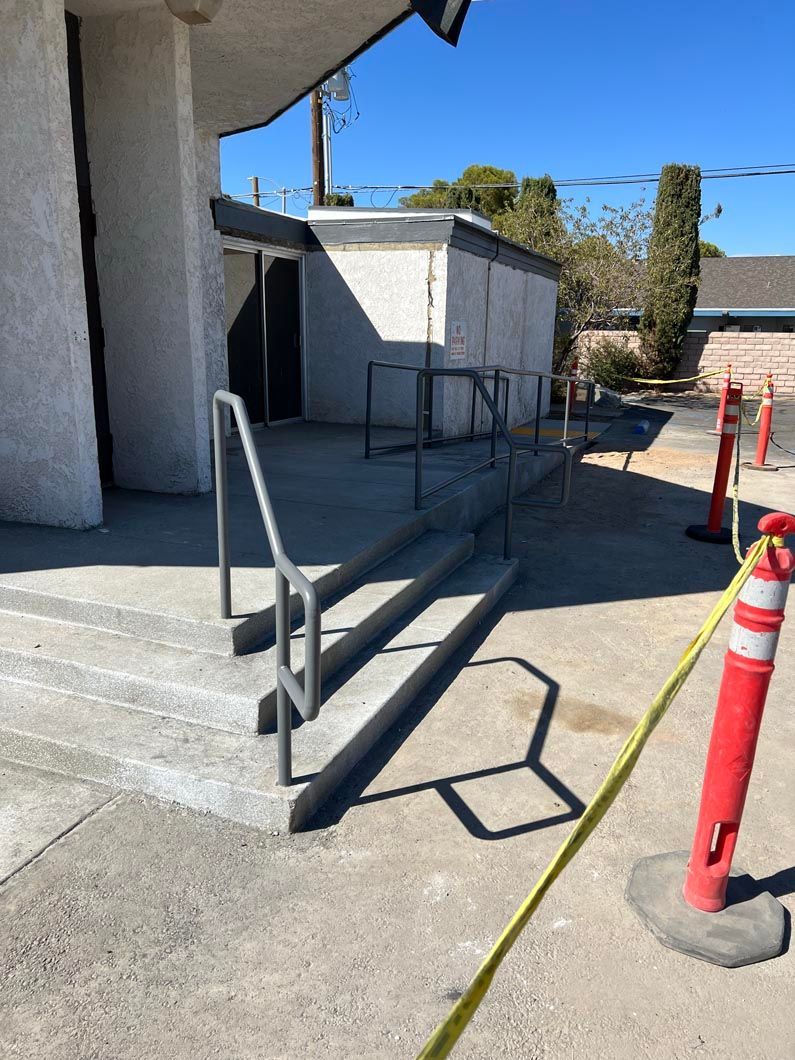 A concrete ramp with a railing and stairs leading up to a building.
