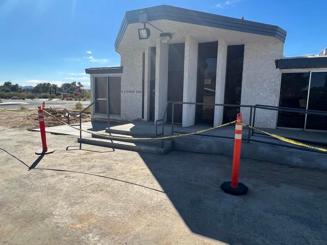A white building with stairs and a red pole in front of it.
