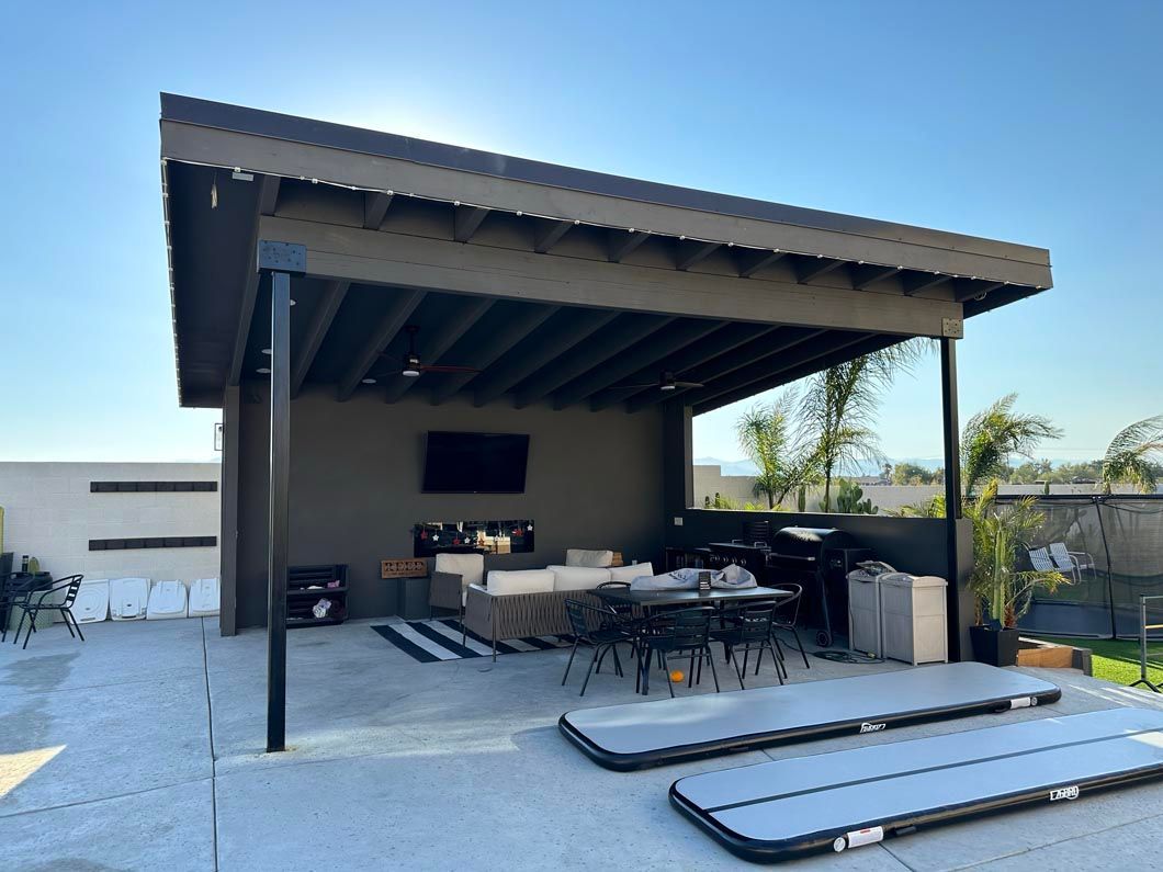 A covered patio with a table and chairs under a roof.