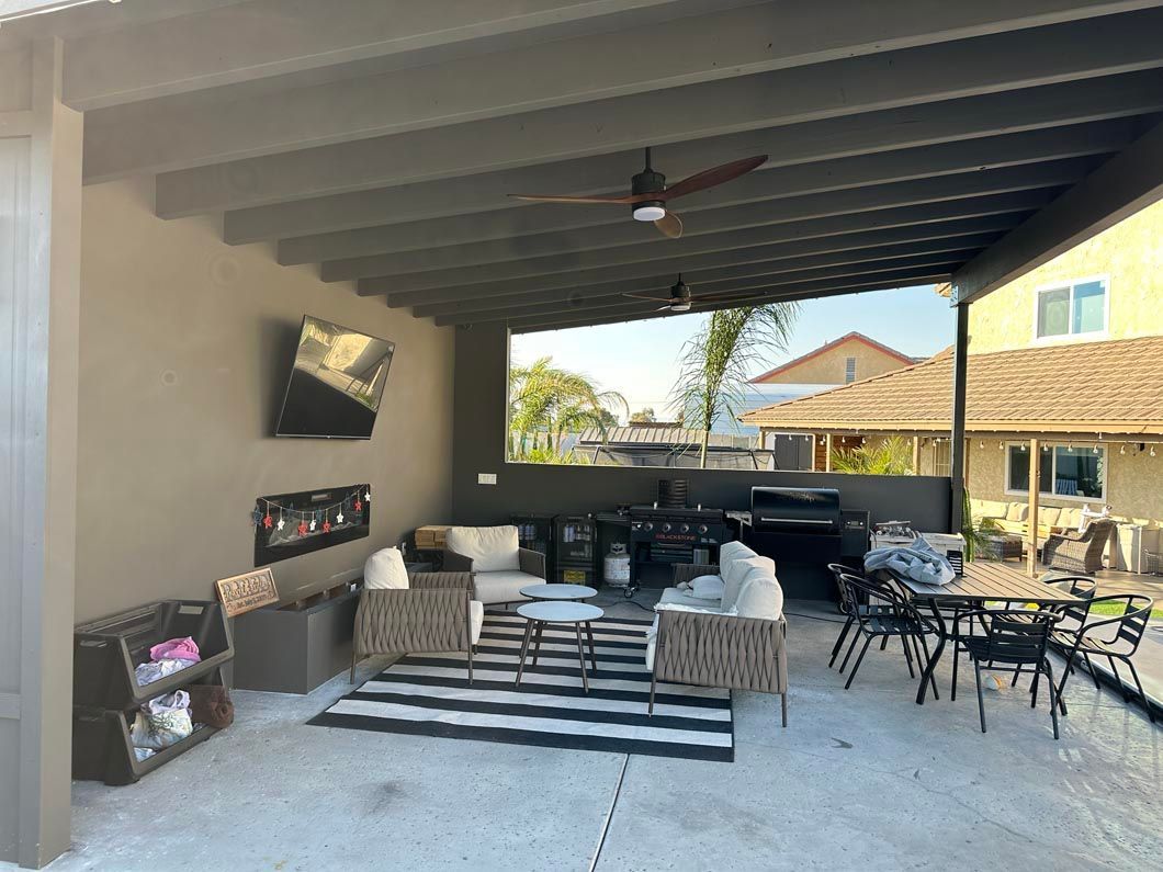 A patio with a ceiling fan , chairs , tables and a rug.