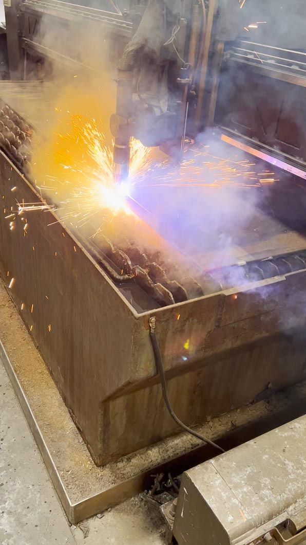 A machine is cutting a piece of metal with a flame coming out of it.