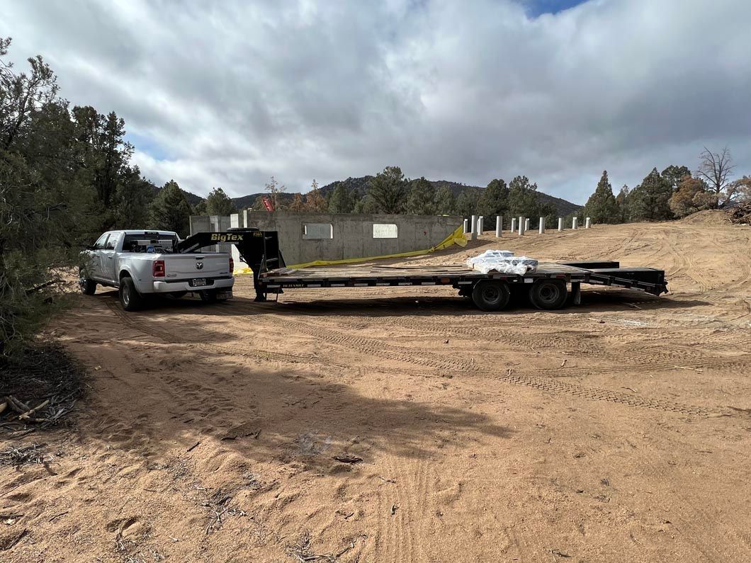 A truck is towing a trailer in a dirt field.