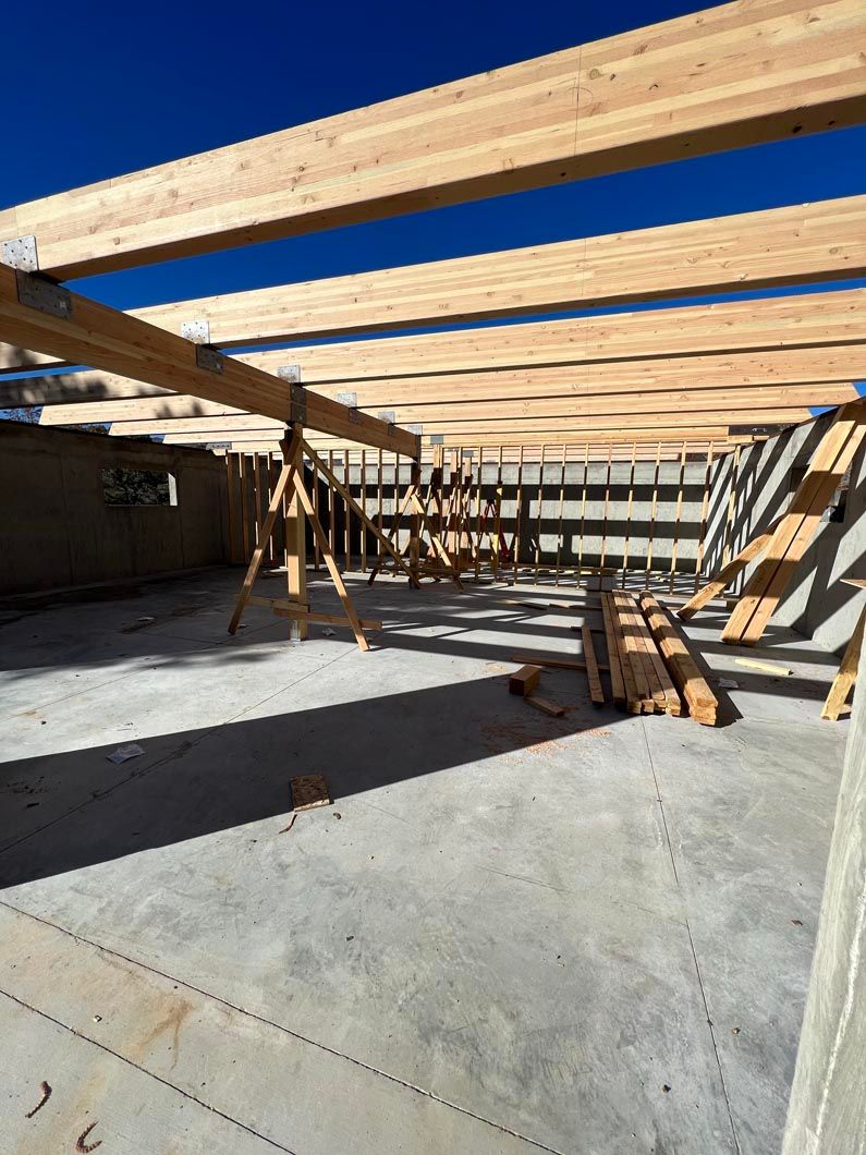 A building under construction with wooden beams and a concrete floor.