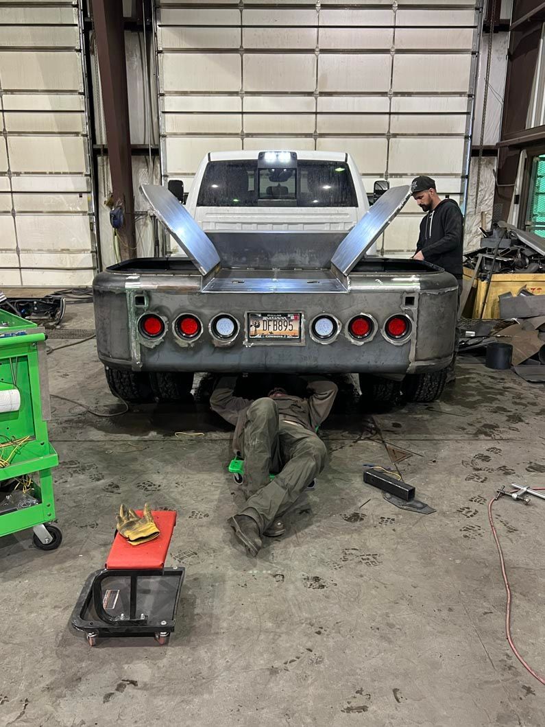 A man is laying under a truck in a garage.