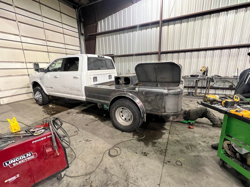 A white truck with a trailer attached to it is in a garage.