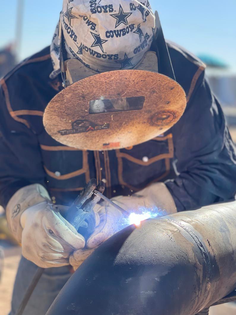 A man wearing a cowboy hat is welding a pipe