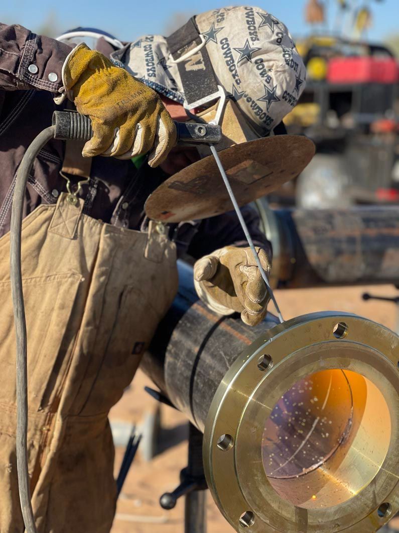 A man wearing gloves is welding a metal pipe