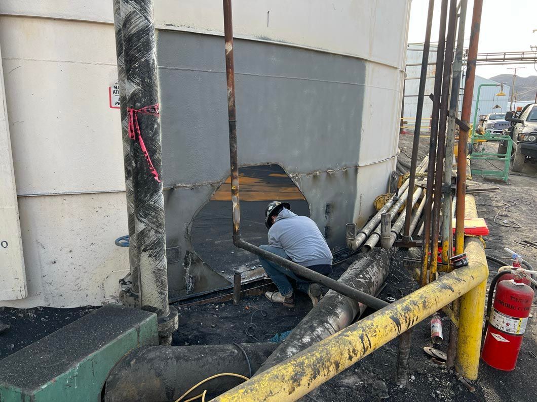 A man is kneeling down in front of a large tank.