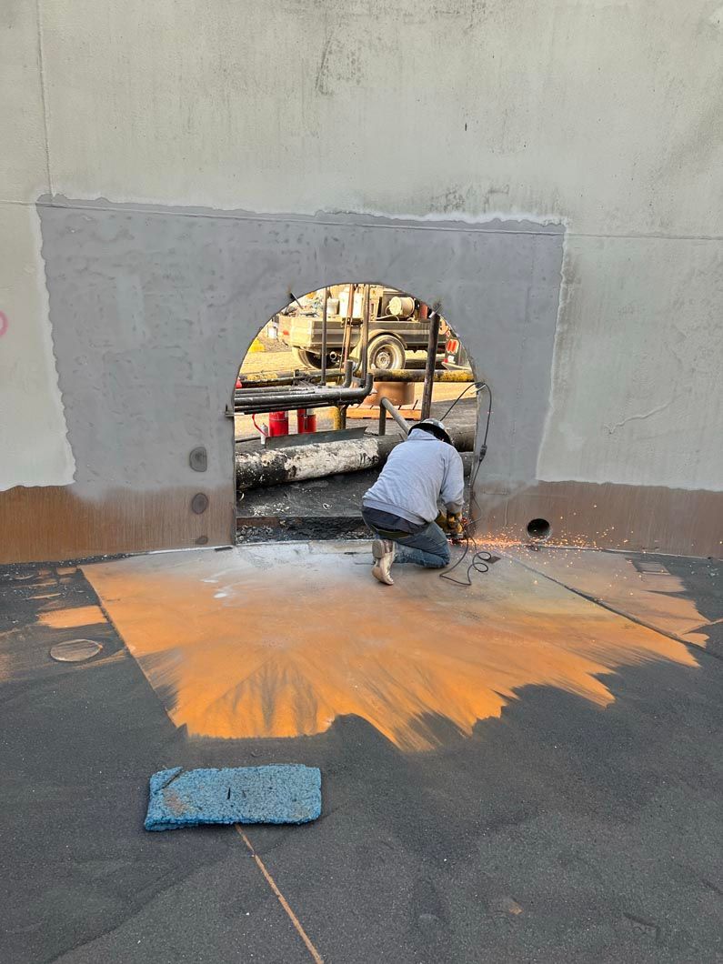 A man is kneeling down in front of a hole in a wall.